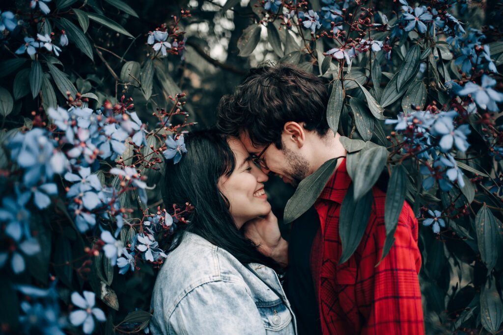 Happy couple sharing a romantic moment surrounded by beautiful blue flowers.